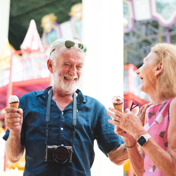 happy senior friend couples enjoy amusement park with ice cream