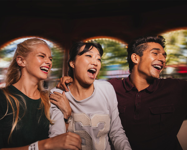 Group of friends on amusement park ride. Young man and women having fun together.