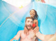Young happy friends having fun in aqua park pipe during weekend holidays - Crazy multi race couple taking selfie photo with funny faces - Summer vacation, travel and love concept
